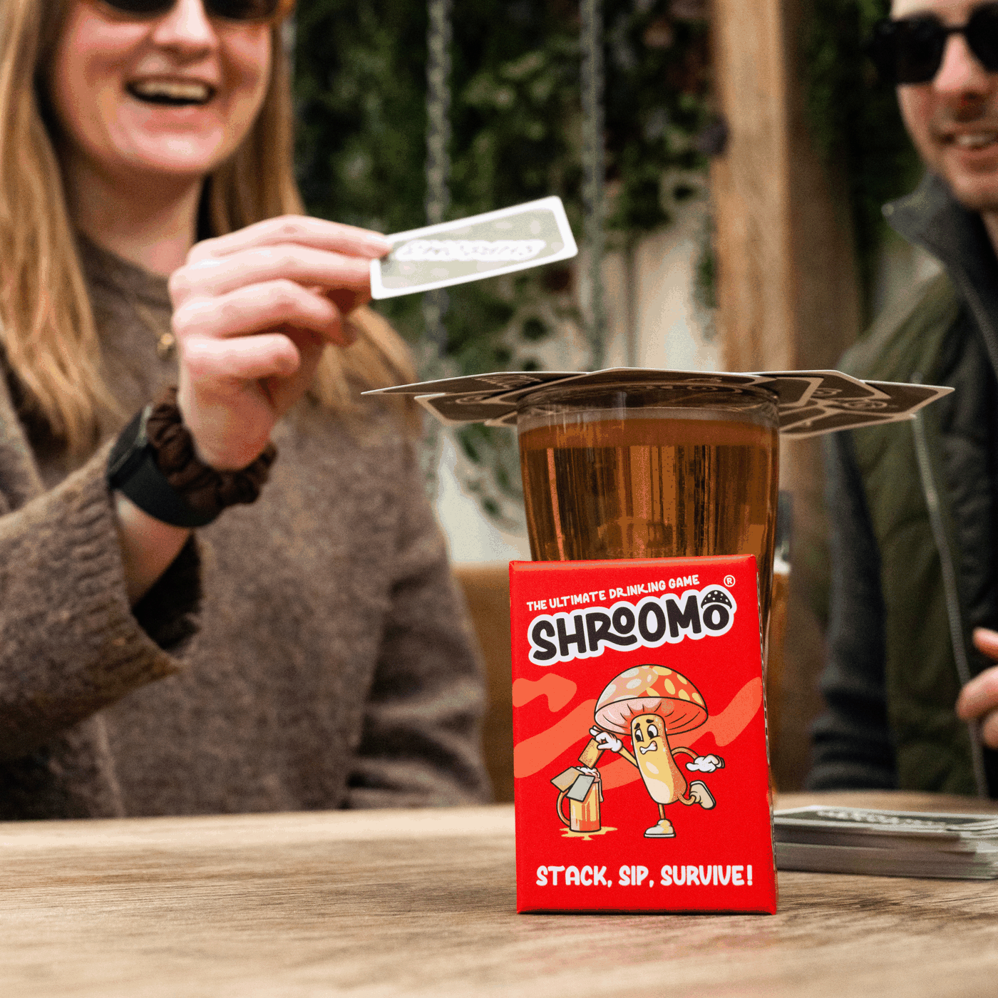 Group of friends laughing while playing the Shroomo drinking game at a house party pre-drinks